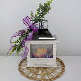 Decorative memorial lantern with greenery and a purple ribbon