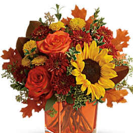 Autumn bouquet with sunflowers, roses, and mums in an orange vase