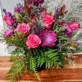 Pink roses and purple blooms in a low black container