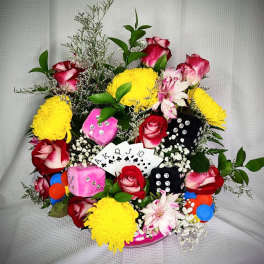 Mixed bouquet with roses, yellow mums, and playing cards in a decorative base