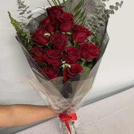 Bouquet of red roses wrapped in dark paper with a red ribbon