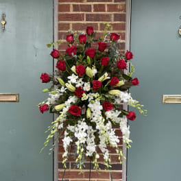 Tall standing floral spray with red roses and white orchids on a metal easel