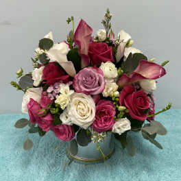 Bouquet of pink and white roses with calla lilies in a round vase