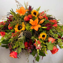 Large arrangement of orange lilies, sunflowers, and roses on a table