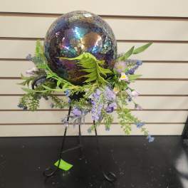 Mosaic egg display surrounded by small purple flowers on a metal stand