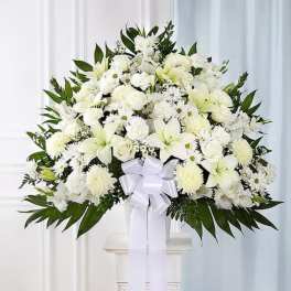 White floral spray with lilies and chrysanthemums in a vase, tied with a white ribbon