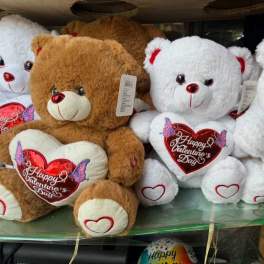 Plush teddy bears holding heart-shaped Valentine’s Day pillows