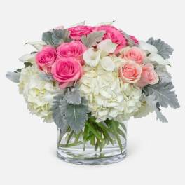 Pink and white roses with hydrangeas in a clear glass vase