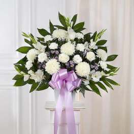 White floral arrangement with a lavender ribbon in a clear vase