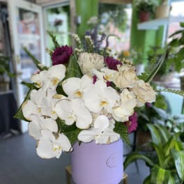 White orchids and purple flowers in a lavender hatbox