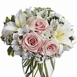 Pink roses and white lilies arranged in a clear glass vase
