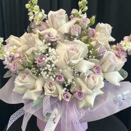 Bouquet of white roses and pale lavender flowers with a ribbon bow