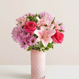 Pink roses and lilies arranged in a tall pink vase