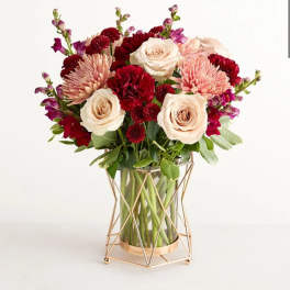 Bouquet of cream roses, pink mums, and red carnations in a glass vase