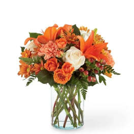 Orange and white flower bouquet in a clear glass vase