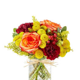 Bouquet of orange roses and yellow and burgundy flowers in a glass vase