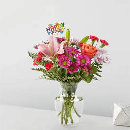 Mixed bouquet in a glass vase with a birthday topper