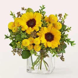 Sunflower and yellow pom bouquet in a clear glass vase