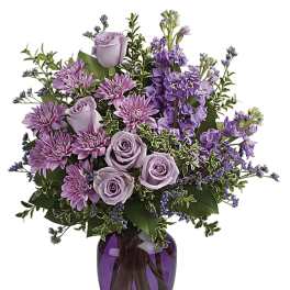 Lavender roses and purple flowers in a purple glass vase