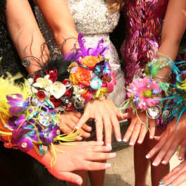 Colorful floral wrist corsages worn by several people
