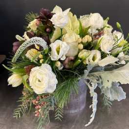 White and cream floral arrangement in a gray vase with trailing greenery