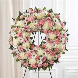 Pink and white floral wreath on a black stand