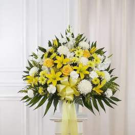 Yellow and white floral arrangement with a ribbon in a clear vase