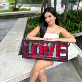 Woman holding a framed LOVE sign filled with red roses