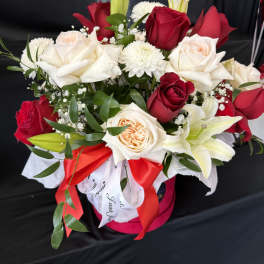 Bouquet of red and white roses with lilies in a pink hat box