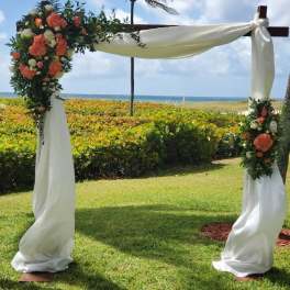 Floral wedding arch with white draping and coral-white flowers