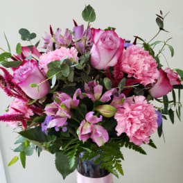 Pink roses and carnations in a purple glass vase