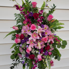 Tall standing floral spray with pink and purple blooms on a metal easel