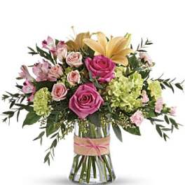 Bouquet of pink roses, lilies, and green hydrangeas in a glass vase