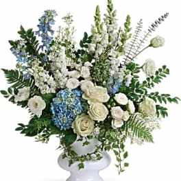 White and blue floral arrangement in a white pedestal vase