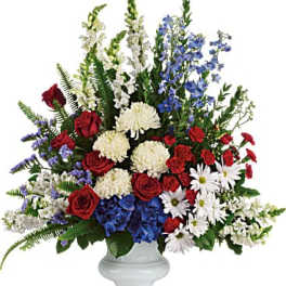 Large mixed flower arrangement in a white vase with red, white, and blue blooms