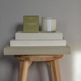 Eucalyptus candle in a glass jar beside its box on stacked books
