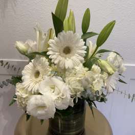 White floral arrangement with gerbera daisies and lilies in a dark vase
