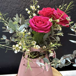 Pink roses in a small pink box with airy white filler flowers