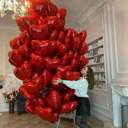 Large cluster of red heart-shaped balloons in a room