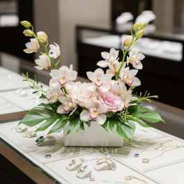 Pink and white orchid arrangement in a white rectangular vase