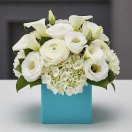 White floral arrangement in a blue square vase