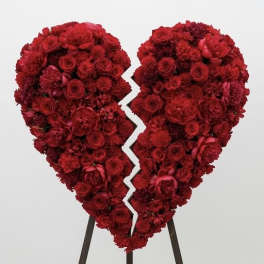 Broken heart-shaped red floral standing spray on an easel