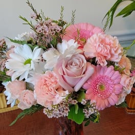 Pink and white mixed bouquet in a red glass vase
