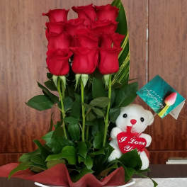 Red roses in a white hatbox with a teddy bear and anniversary tag