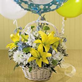 Basket of yellow lilies and white flowers with baby boy balloons