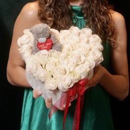 Heart-shaped bouquet of white roses with a small teddy bear and red ribbon