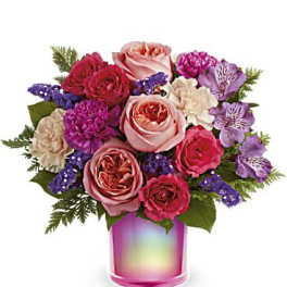 Mixed bouquet of pink and purple flowers in a rainbow glass vase