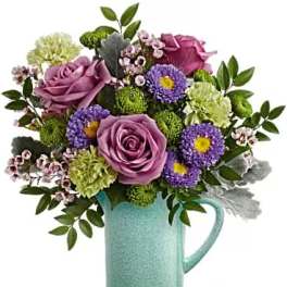 Purple roses and mixed flowers in a turquoise pitcher vase