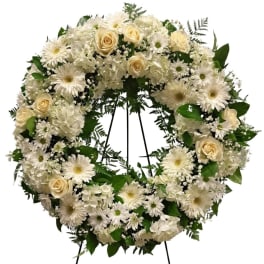 White floral wreath with roses, daisies, and hydrangeas on a stand