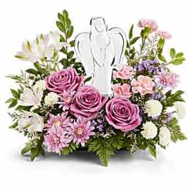 Low arrangement of pink and lavender flowers surrounding a clear angel figurine